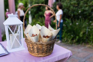 At outdoor wedding, basket of snacks on table with guests mingling nearby