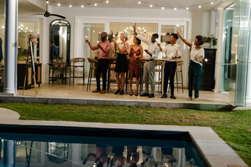Friends celebrating with sparklers by poolside at evening wedding reception