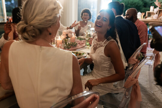 Bride laughing joyfully with guests at elegant wedding reception dinner