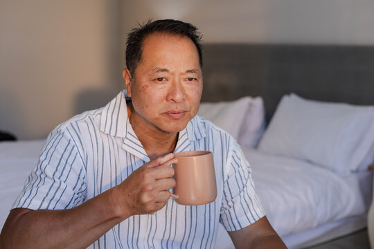 Relaxing at home, senior man enjoying morning coffee in cozy bedroom - Powered by Adobe