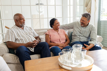 Seniors sitting on couch at home, laughing and enjoying conversation together