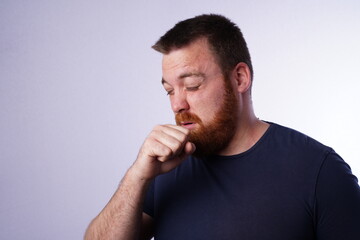 Young guy with ginger beard coughing in his hand.