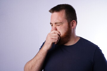 Young guy with ginger beard coughing in his hand.