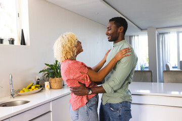 African American couple embracing in modern kitchen, sharing joyful moment together