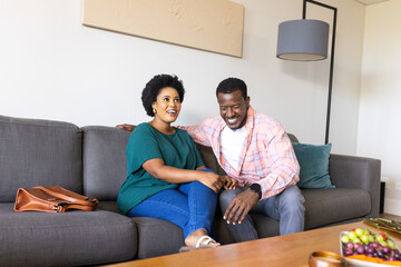 Laughing together on sofa, friends having casual conversation and relaxing at home