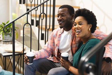 Smiling friends enjoying coffee together on staircase, sharing joyful conversation