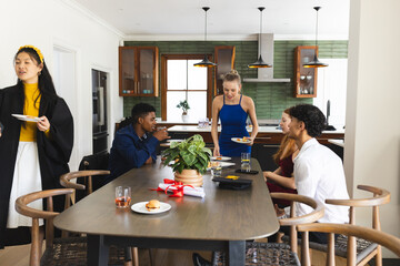 Teens enjoying lively celebration at home, sharing food and laughter around table