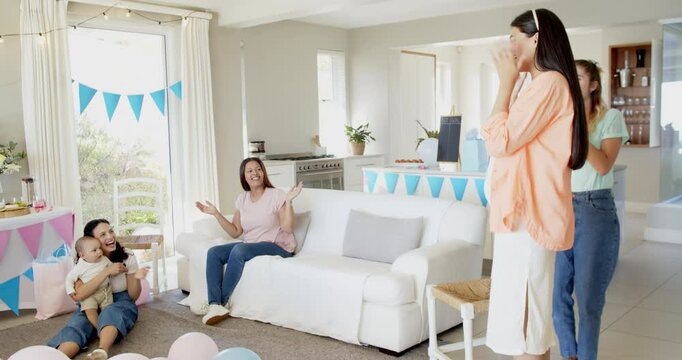 Group of happy multiracial, white and black female friends with babies talking at a baby shower part