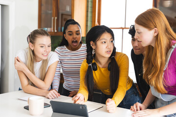 Teenagers collaborating on school project using tablet in modern kitchen setting