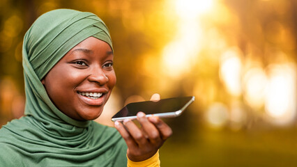 Happy Black Muslim Woman In Hijab Recording Voice Message On Smartphone, African Islamic Lady Using...