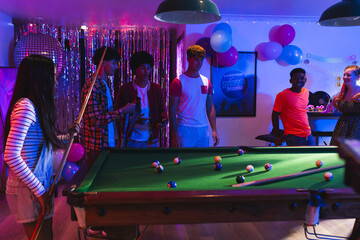 Teenagers playing pool at lively party, enjoying vibrant celebration with friends