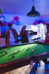 Fototapeta premium Teenagers enjoying birthday party playing pool in festive decorated room