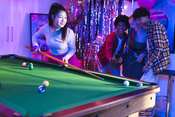 Teenagers playing pool at birthday party, enjoying celebration with friends