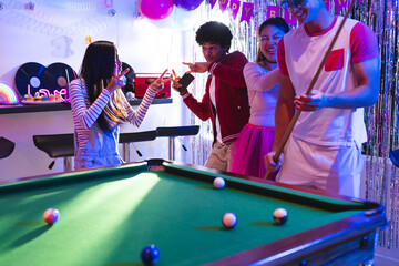 Fototapeta premium Teens celebrating at home, playing pool and enjoying lively party atmosphere