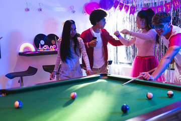 Teenagers playing pool and celebrating birthday in colorful party room