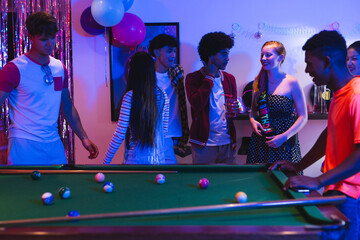 Fototapeta premium Teenagers enjoying lively pool game at home party with colorful decorations