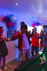 Fototapeta premium Celebrating with balloons, teenagers having festive party around pool table