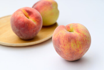 Peaches fruit on wooden plate with white background