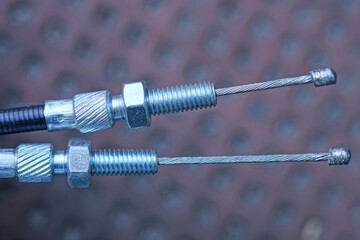 part of gray metal brake cables for motorcycle on brown background on city street