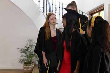 Graduating students in caps and gowns celebrating together at home