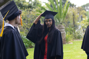 Teen graduates in cap and gown celebrating outdoors, enjoying their achievement