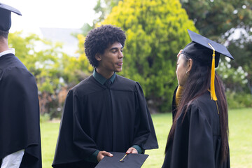 Graduating students in caps and gowns celebrating outdoors, sharing joyful moments