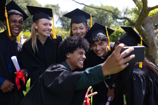 Graduating students taking selfie outdoors, celebrating with joy and excitement