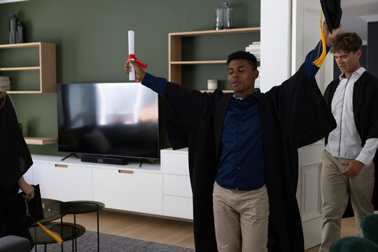 Teen celebrating graduation at home, holding diploma with joyful expression