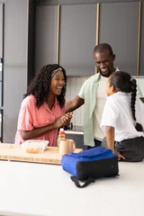 Selbstklebende Fototapeten African American family in kitchen, smiling and preparing lunch together at home © WavebreakMediaMicro