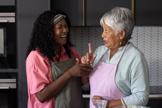 African American woman and elderly woman laughing together in kitchen while cooking