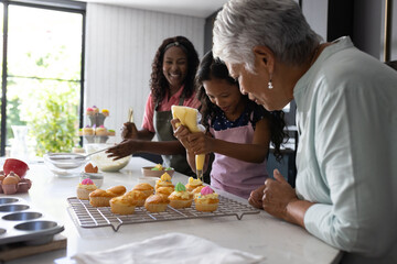 Baking cupcakes, three generations decorating with icing, sharing joyful family moments