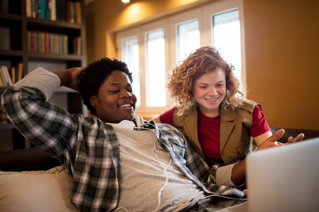 Happy friends watching something on a laptop together at home