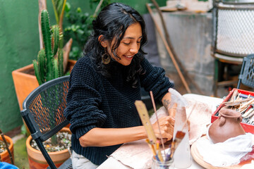 Concentrating on her craft, a talented craftswoman skillfully shapes clay in her vibrant workshop, surrounded by plants and artistic tools