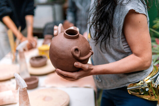 Potter displaying a handmade clay vase during a pottery workshop, highlighting the artistry and skill involved in the creative process - Powered by Adobe