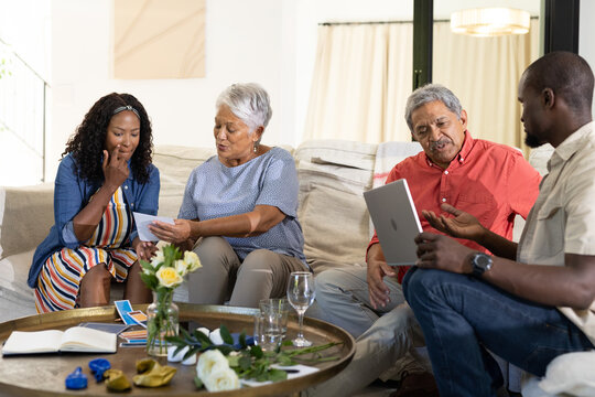 Sharing photos, African American woman with elders and man using tablet at gathering
