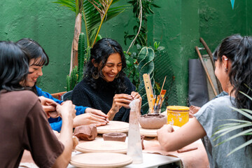 Group of Latin women engaged in creating handmade ceramic pieces during an inspiring pottery...
