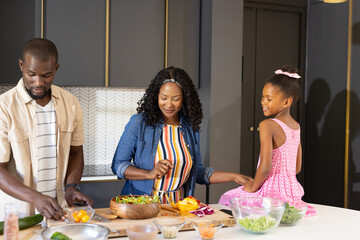 African American family preparing healthy meal together in modern kitchen, smiling
