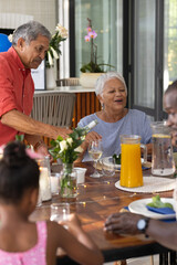 Family sharing meal at home, laughing and conversing around dining table