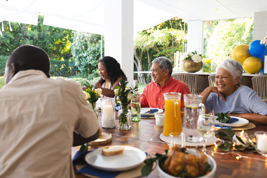 Family enjoying outdoor meal together, smiling and sharing stories at festive table