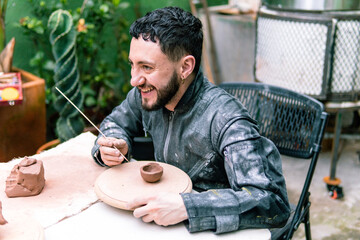 Potter refining a small clay bowl with a wooden stick, skillfully crafting in a vibrant workshop...