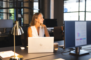 Analyzing data on computer screen, businesswoman working late in office, looking thoughtful