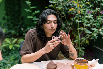 Young ceramist carefully molding a small clay vase during a pottery workshop, focusing on the...