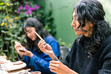 Two craftswomen painting ceramic pieces in a pottery workshop, skillfully using brushes and various tools to create unique artwork