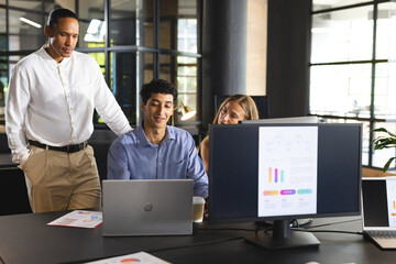 Business team collaborating on project with laptops and charts in modern office