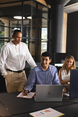 Fototapeta premium Collaborating in modern office, business professionals discussing project details on laptop