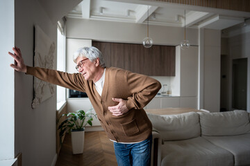 Afflicted senior man feel severe retrosternal pain with breathing difficulty, gripping chest. Myocardial ischemia, coronary insufficiency, radiating arm pain, autonomic symptoms, emergency pain