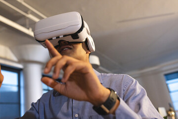 Using VR headset, man interacting with virtual environment in office enthusiastically