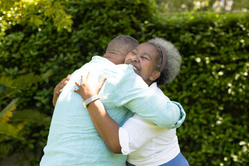 Senior couple embracing joyfully in garden, sharing warm and loving hug
