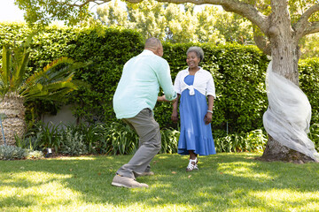 Fototapeta premium In garden, senior couple having playful moment together surrounded by greenery