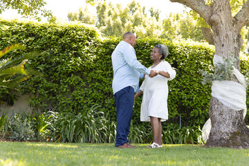 Senior couple dancing joyfully together in sunny garden, enjoying outdoor moment © WavebreakMediaMicro